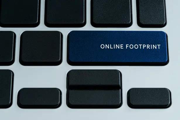 A close-up of a computer keyboard with a prominent blue key labeled "ONLINE FOOTPRINT" among black keys.